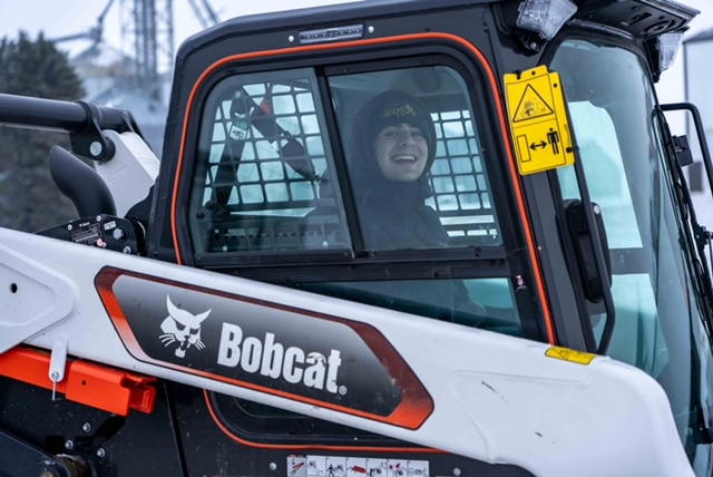 man smiling from inside a bobcat excavator